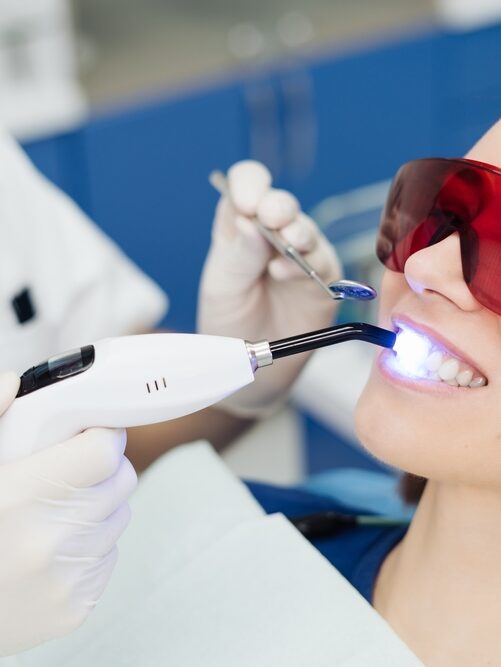 Female patient receiving painless laser dental treatment during a routine dentist visit.